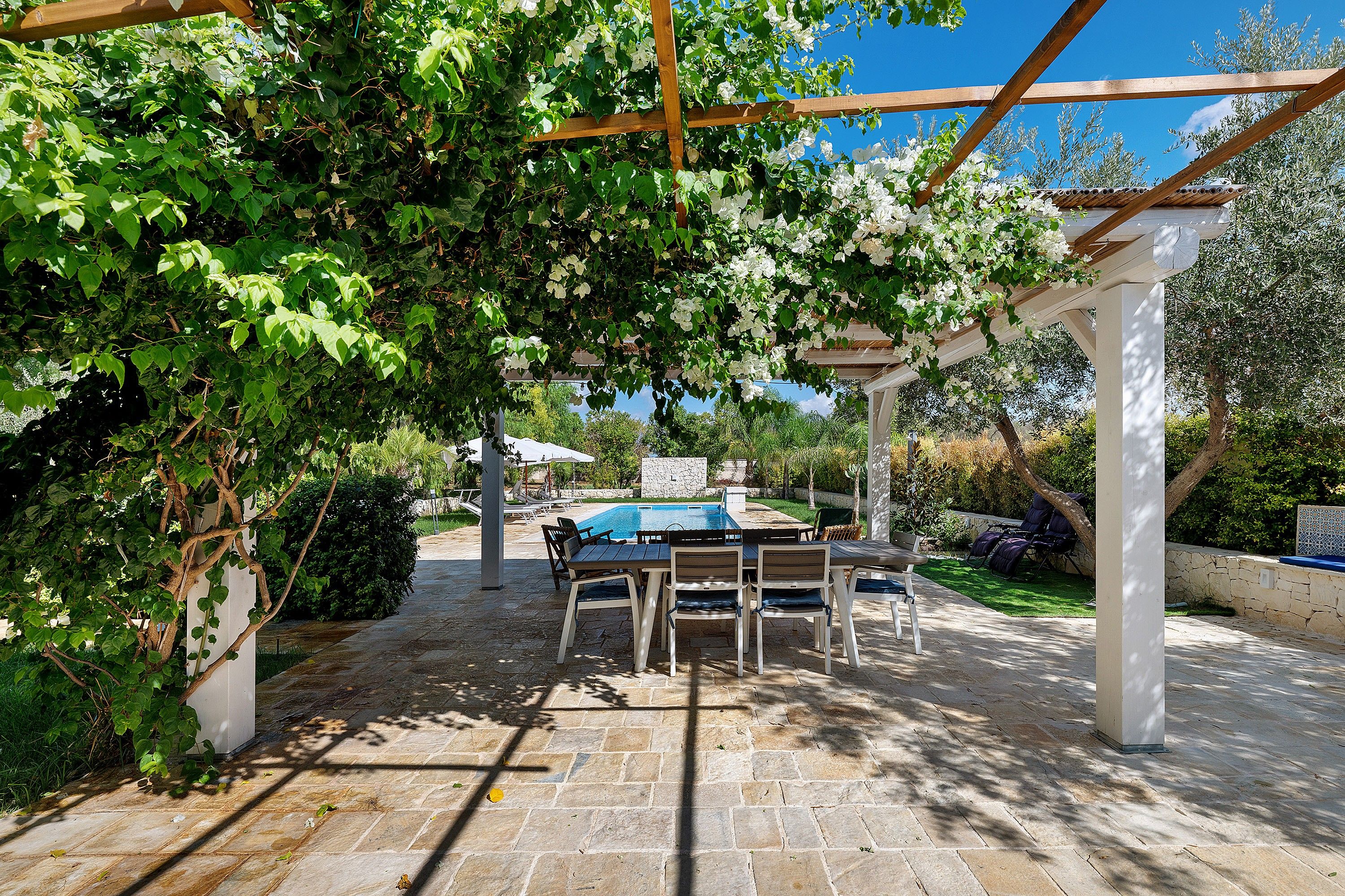 Eine Terrasse im Freien mit Pergola, Steinboden und einem Billardtisch.