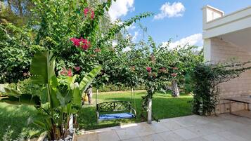 Un giardino con una panchina, un muro bianco e un cielo sereno.