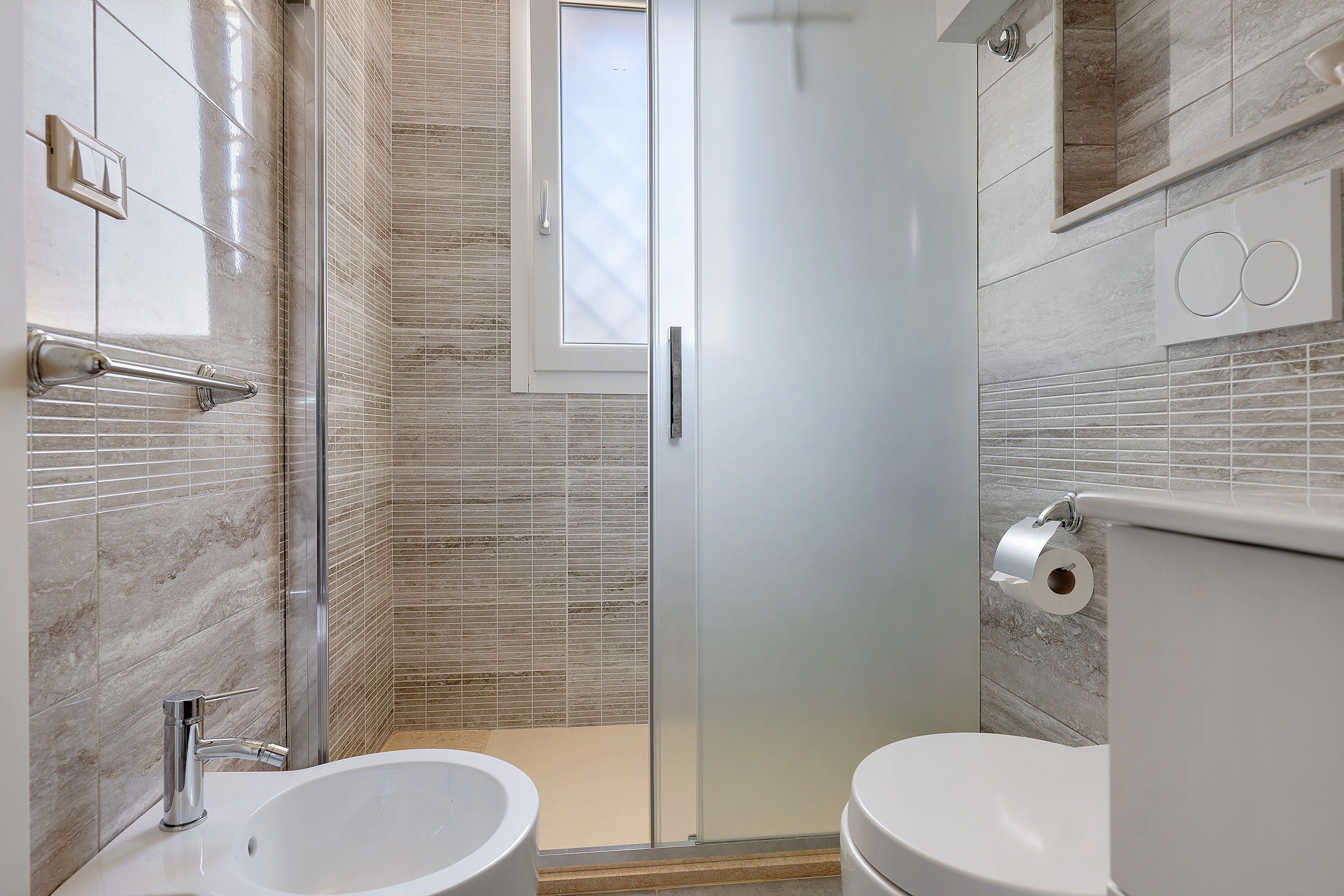Un baño moderno con cabina de ducha de vidrio, inodoro y lavamanos.