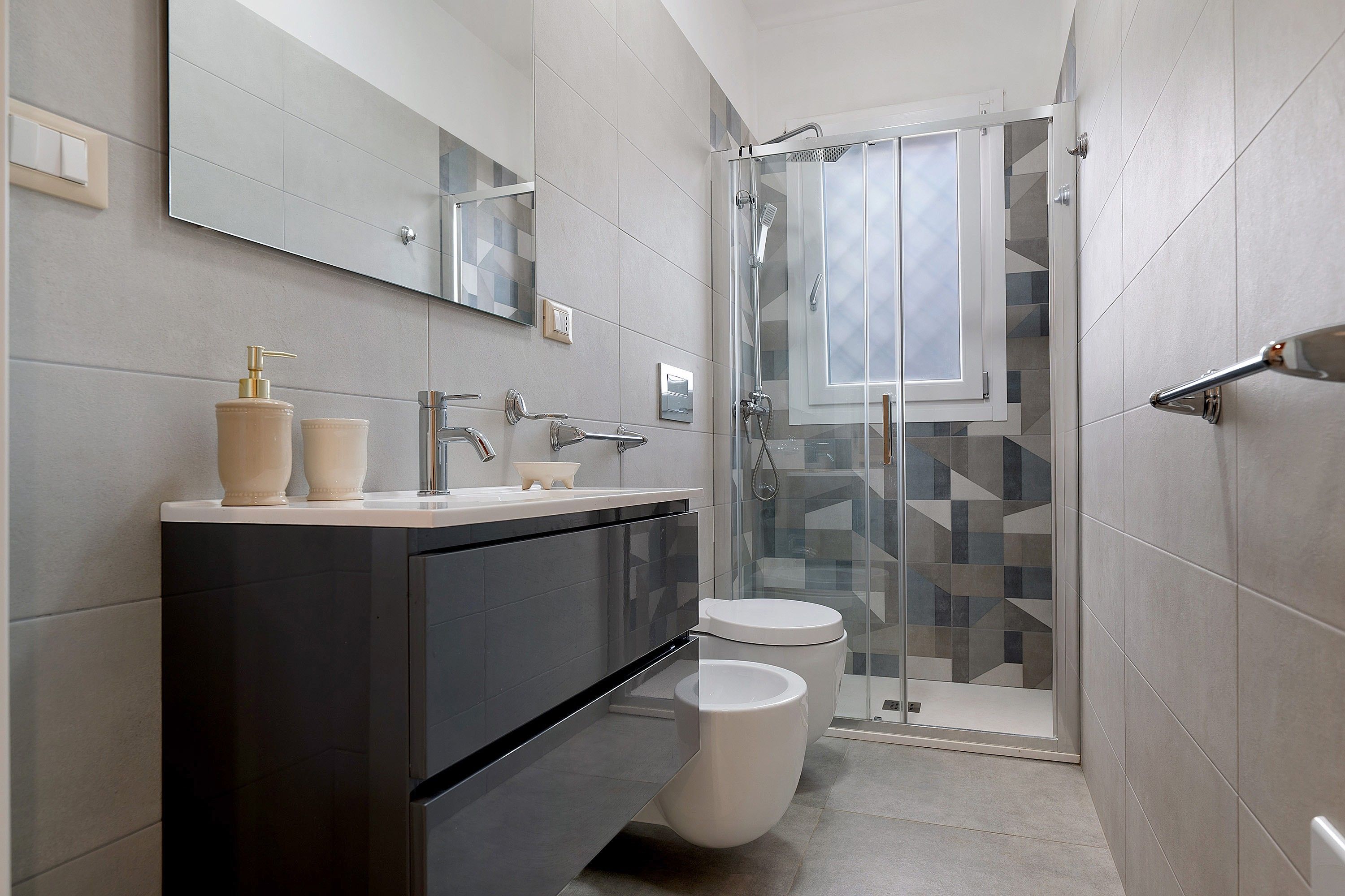 Un bagno moderno con un mobile lavabo scuro, un water e un box doccia in vetro.