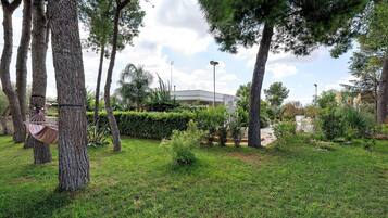 A landscaped garden with trees, a hammock, and a building in the background.