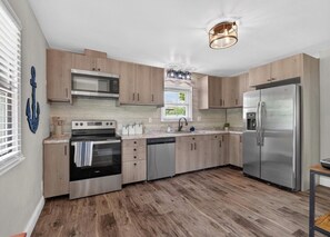 Eine moderne Küche mit Holzausstattung, Edelstahlgeräten und einem Fenster, das für natürliches Licht sorgt.