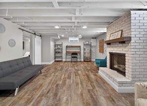 Ein modernes Wohnzimmer mit Kamin, Holzboden und einer Couch.