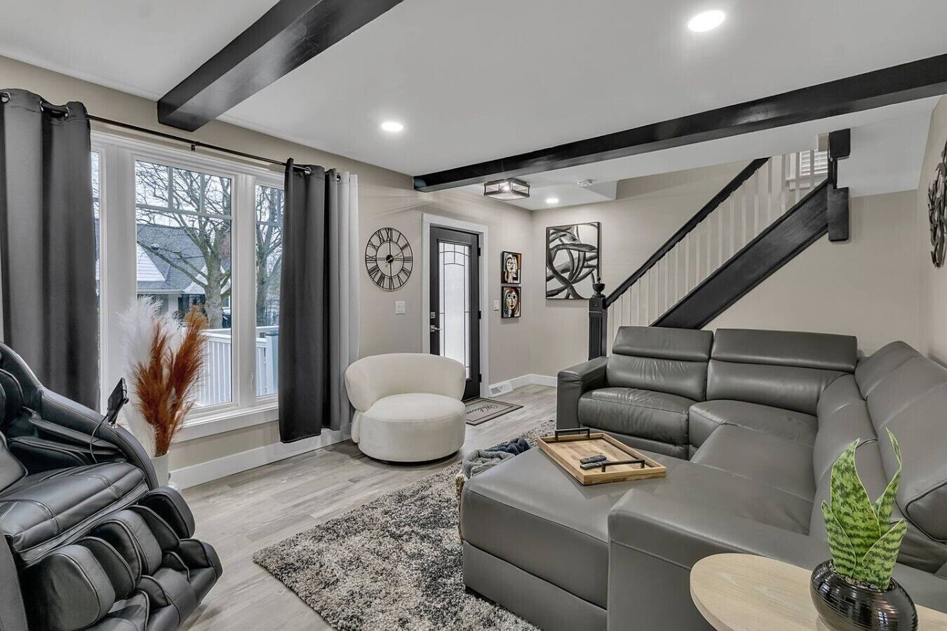 Ein modernes Wohnzimmer mit einer Couch, einem Sessel und einer Treppe.