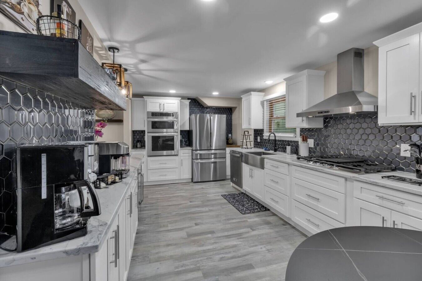 A modern kitchen with white cabinets, stainless steel appliances, and a hexagonal tile backsplash.