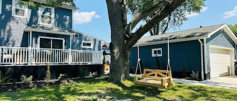 A residential property with a large tree, a swing set, and a garage.