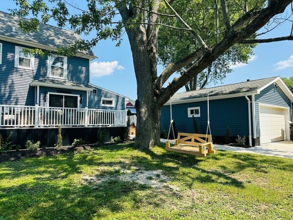 A residential property with a large tree, a swing set, and a garage.