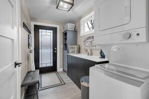 A laundry room with a washing machine, a drying rack, and a wall-mounted drying unit.