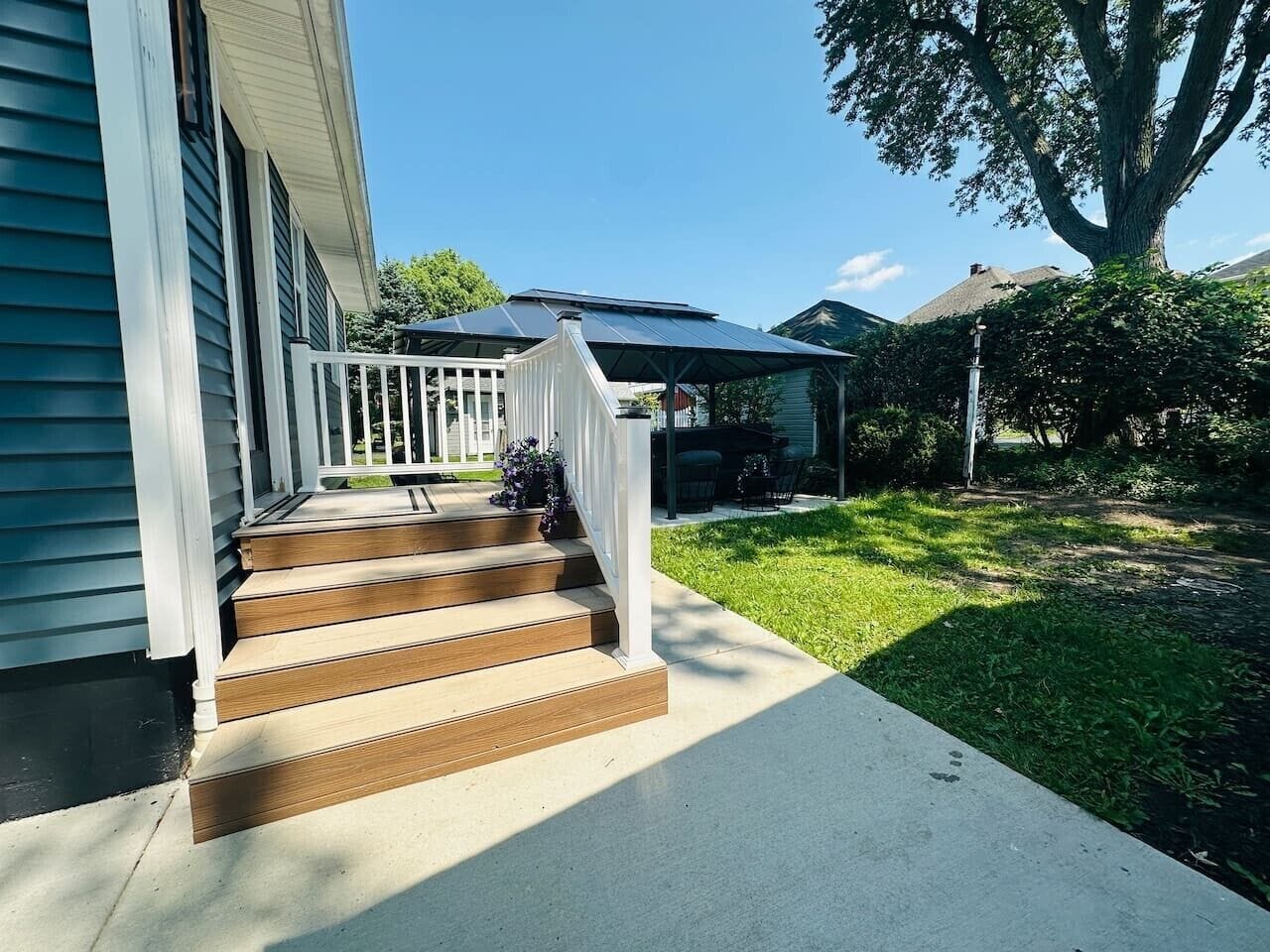 A residential property with a front porch, wooden steps, and a covered area with outdoor furniture.