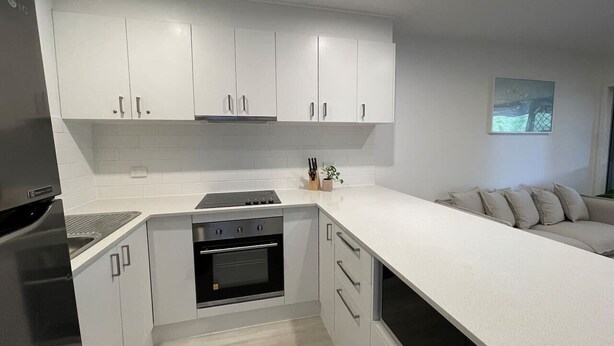 A modern kitchen with white cabinetry, a built-in oven, and a countertop. - Killara Apt 1 - Noosa Heads Holiday Apartment (Noosa Heads)