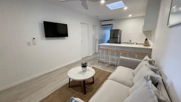 A modern living room with a sofa, a coffee table, and a TV.