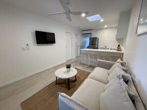 A modern living room with a sofa, a coffee table, and a TV. - Killara Apt 1 - Noosa Heads Holiday Apartment (Noosa Heads)