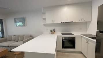 A modern kitchen with white cabinetry, a built-in oven, and a stainless steel refrigerator.