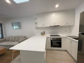 Eine moderne Küche mit weißen Schränken, einem eingebauten Backofen und einem Edelstahl-Kühlschrank.