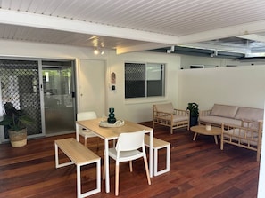 A room with a wooden floor, a dining table with chairs, a sofa, and a potted plant. - Killara Apt 2 - Noosa Heads Holiday Apartment (Noosa Heads)