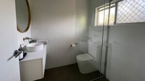 A bathroom with a white sink, toilet, and a glass shower enclosure. - Killara Apt 4 - Noosa Heads Holiday Apartment (Noosa Heads)