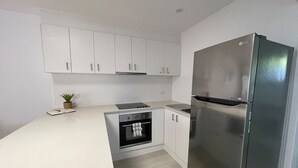 A modern kitchen with white cabinets, a stainless steel refrigerator, and a built-in oven. - Killara Apt 4 - Noosa Heads Holiday Apartment (Noosa Heads)