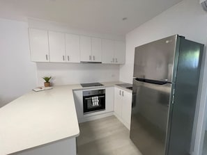 A modern kitchen with white cabinets, a stainless steel refrigerator, and a built-in oven. - Killara Apt 4 - Noosa Heads Holiday Apartment (Noosa Heads)