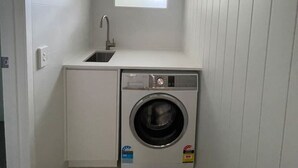 A compact laundry room with a built-in washer and dryer, a small window, and a sink. - Killara Apt 4 - Noosa Heads Holiday Apartment (Noosa Heads)