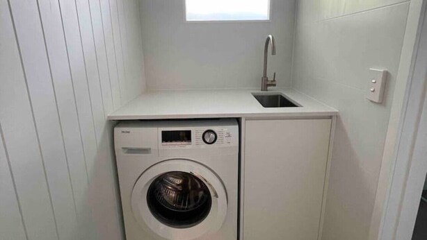 A compact laundry room with a built-in washer and dryer, a small window, and a sink. - Killara Apt 3 - Noosa Heads Holiday Apartment (Noosa Heads)