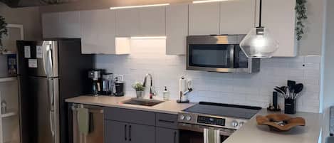 Una cocina moderna con electrodomésticos de acero inoxidable, armarios grises y piso de madera.