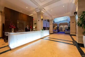 A hotel lobby with a reception desk, a large chandelier, and a marble floor. - Down town Industrial Loft w/ Exposed Brick (Houston)