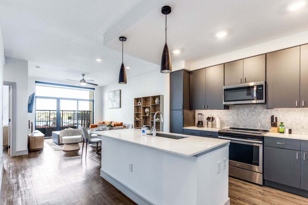 A modern kitchen with a central island, stainless steel appliances, and dark cabinetry.