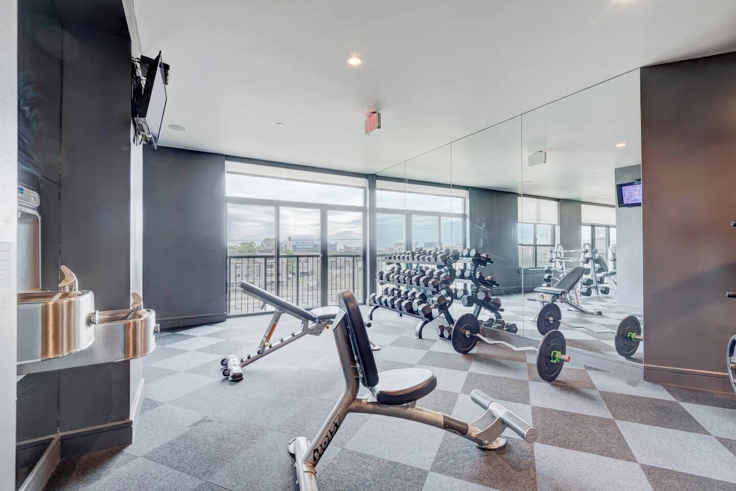 A gym with weightlifting equipment, a rowing machine, and a large window.