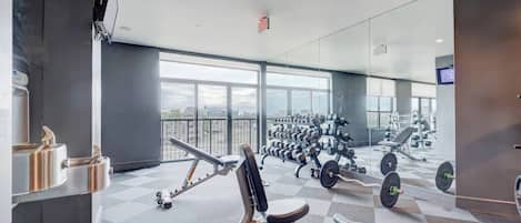 Une salle de sport équipée de matériel de musculation, d’un rameur et dotée d’une grande fenêtre.