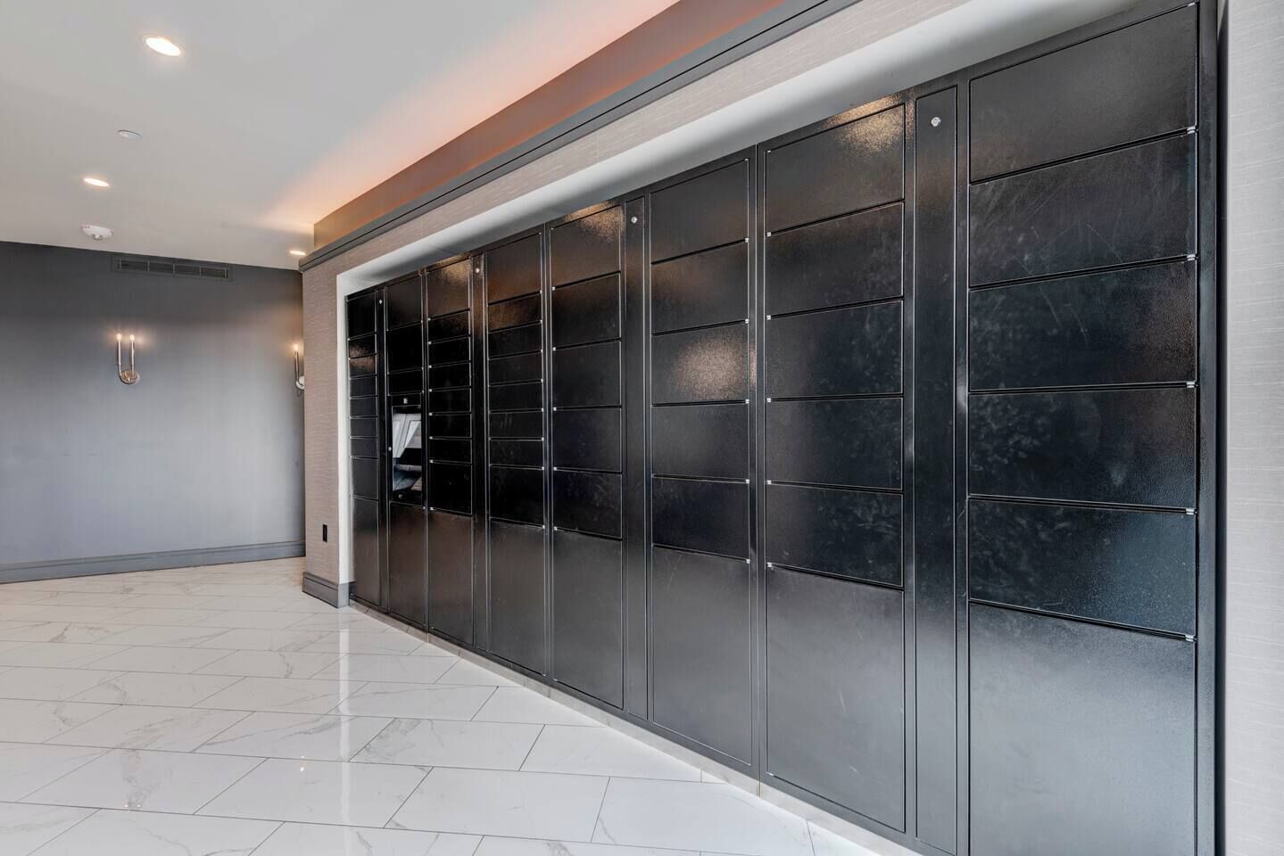 A modern interior with a large, dark-colored storage unit against a wall, a clean tiled floor, and recessed ceiling lighting.
