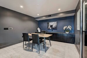 Eine moderne Küche mit dunkelblauer Akzentwand, einem Holzesstisch und schwarzen Stühlen.