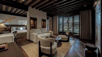 Una sala de estar moderna con sofá, sillones, una mesa de centro y una chimenea. Hay un ventanal con cortinas y vistas al exterior.