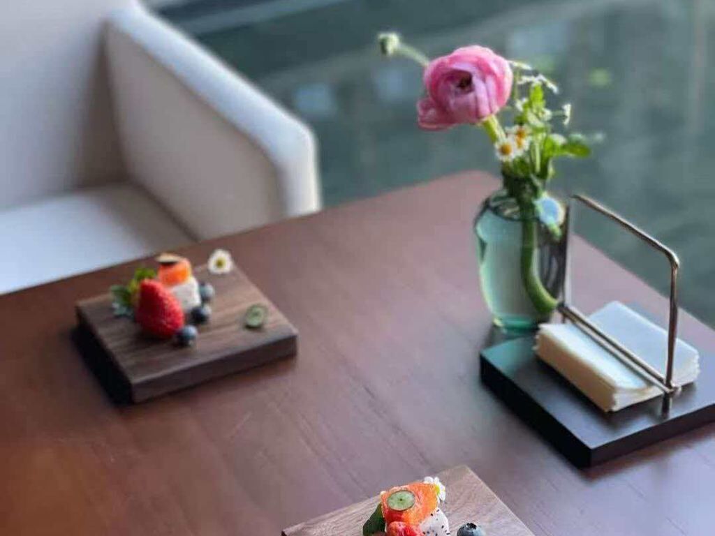 Una mesa de comedor con un florero y un pequeño soporte de metal.