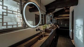 Un baño moderno con un tocador alargado, varios espejos y una ventana con diseño geométrico.