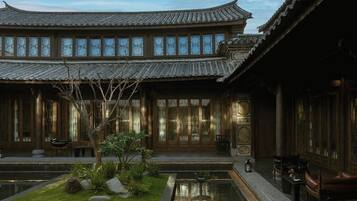 Un edificio tradicional con un patio, un estanque y mobiliario de madera.