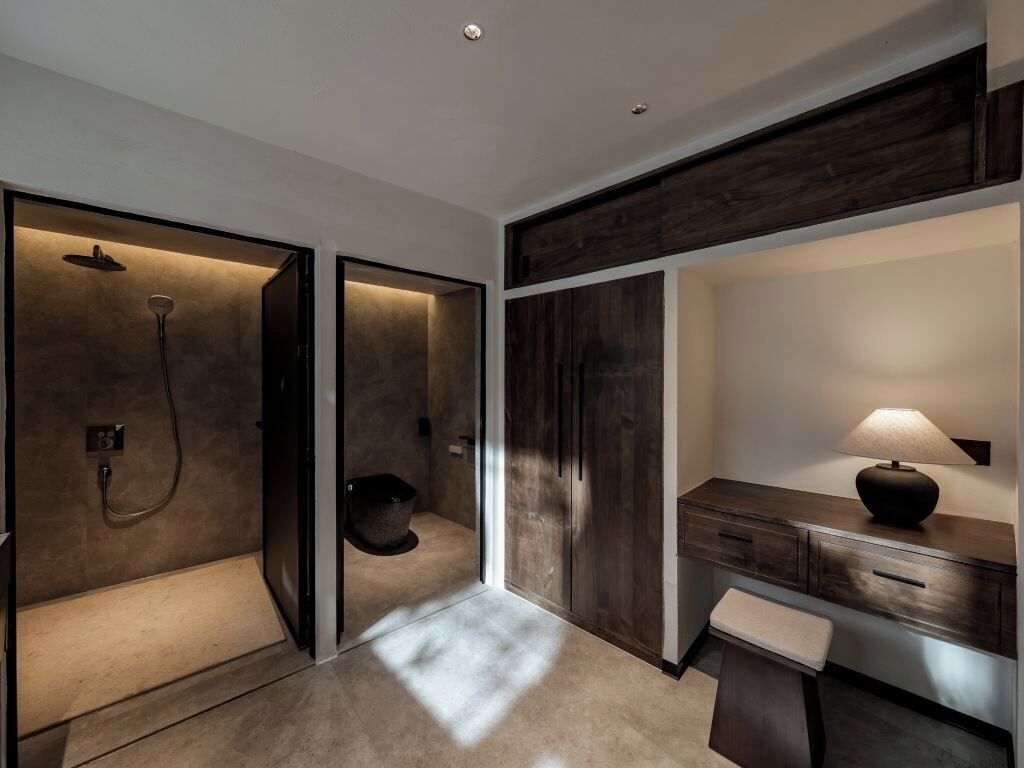 A modern bathroom with a walk-in shower, a vanity with a mirror, and a bench.