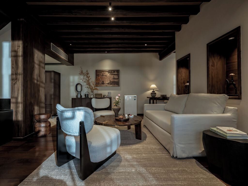Una sala de estar moderna con un sofá, un sillón, una mesa de centro y un cuadro en la pared.