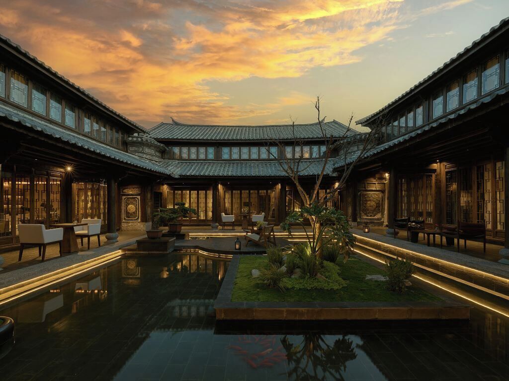 Un patio tradicional con un estanque reflectante, edificios de madera y zonas de estar.
