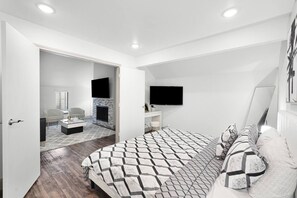 Een moderne slaapkamer met een bed, een televisie en een open haard.
