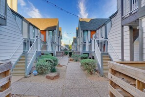 A row of two-story buildings with wooden railings and a gravel pathway. - LUXE King Bed Getaway | Pool & Hot Tub | NRG & TMC (Houston)