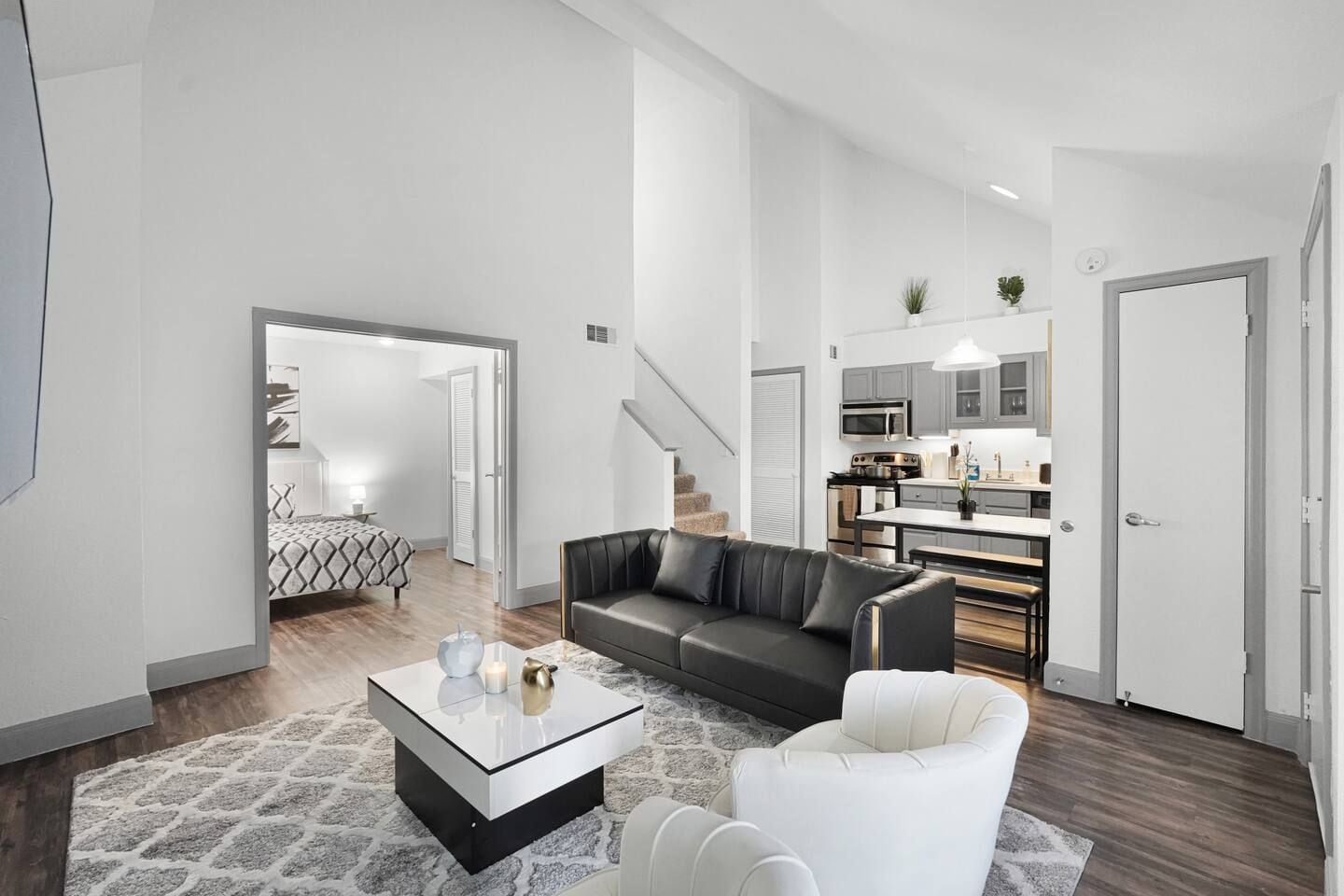 Een moderne woonkamer met een leren bank, een witte fauteuil en een glazen salontafel.