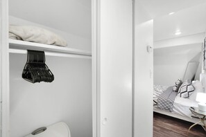 A room with a bed, a chair, and a wardrobe with hanging clothes. - LUXE King Bed Getaway | Pool & Hot Tub | NRG & TMC (Houston)