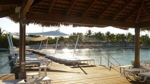 A wooden deck with lounge chairs and tables, overlooking a calm body of water with palm trees in the background. - Unknown Accommodation by Interhome (Bayahibe)
