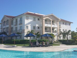 A multi-story hotel with a swimming pool, outdoor seating, and palm trees. - Unknown Accommodation by Interhome (Bayahibe)