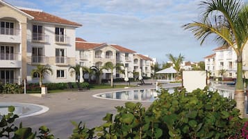 Ein Resort mit mehrstöckigen Gebäuden, einem zentralen Poolbereich und umgebender Bepflanzung.