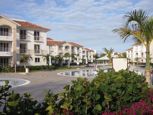A resort with multiple-story buildings, a central pool area, and surrounding greenery.