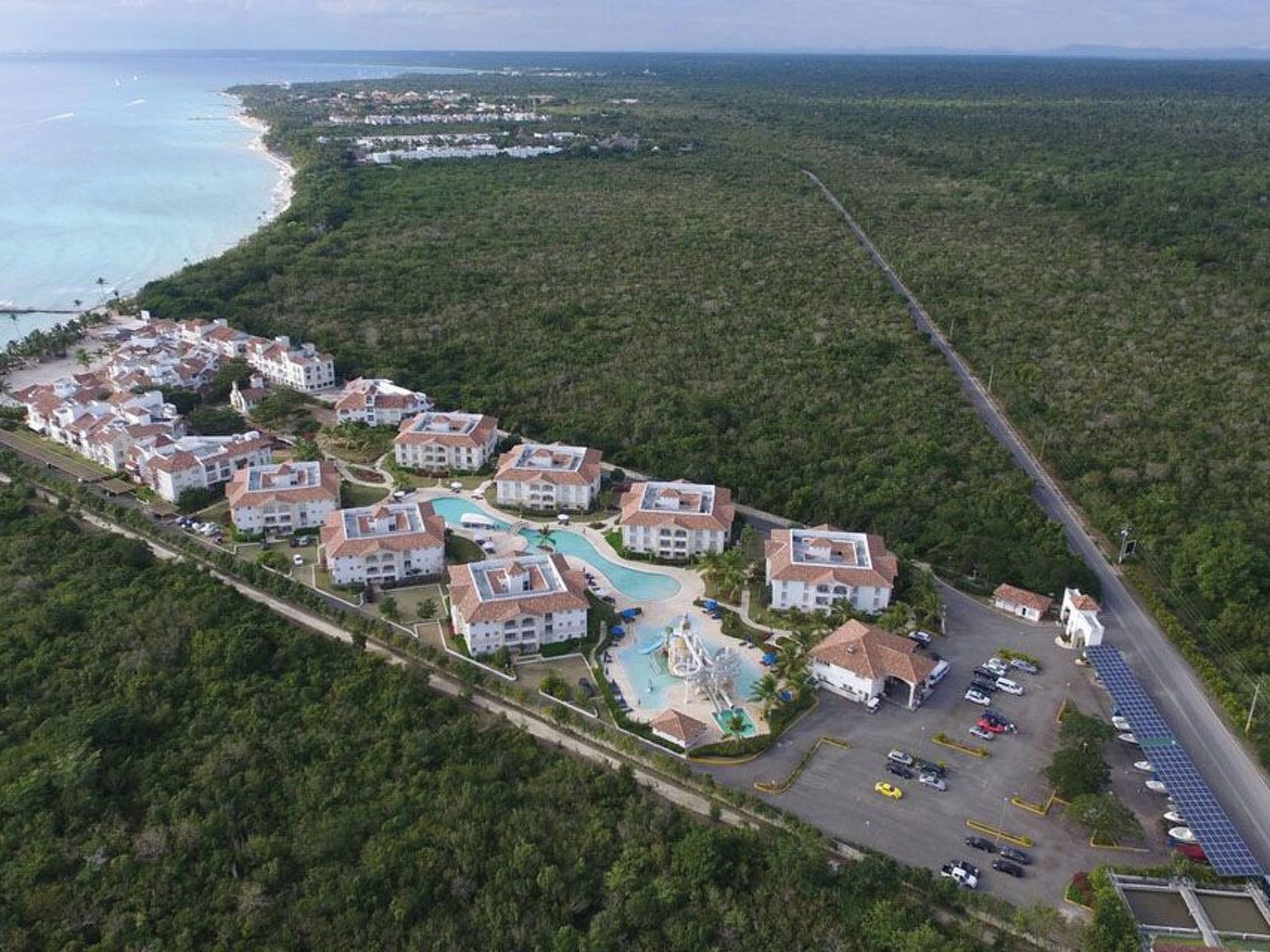 Un resort con varias edificaciones, piscina y zona de estacionamiento.
