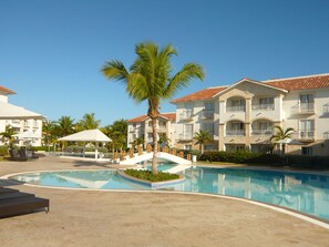 A resort with a swimming pool, palm trees, and multi-story buildings with balconies. - Unknown Accommodation by Interhome (Bayahibe)