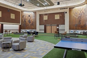 Un espace intérieur spacieux comprenant une table de ping-pong, des sièges confortables et des œuvres d’art accrochées aux murs.