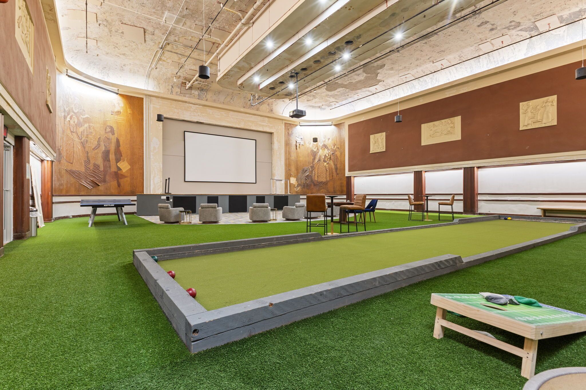 Une salle de billard dotée d’un revêtement de sol vert en gazon synthétique, d’une table de billard et de coins salon.